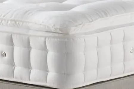 Hand pressing the cushioned top of a pillowtop mattress at BoxDrop Daytona Beach