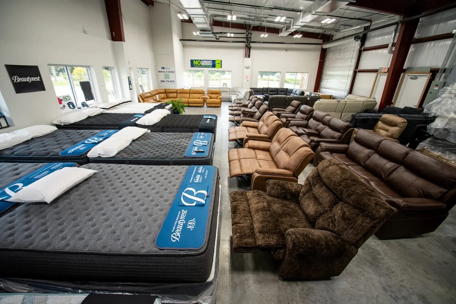 Mattresses and recliners on the floor at the BoxDrop Daytona Beach showroom